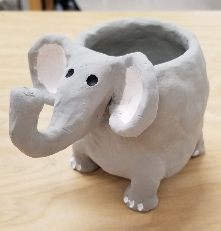 an elephant shaped vase sitting on top of a wooden table