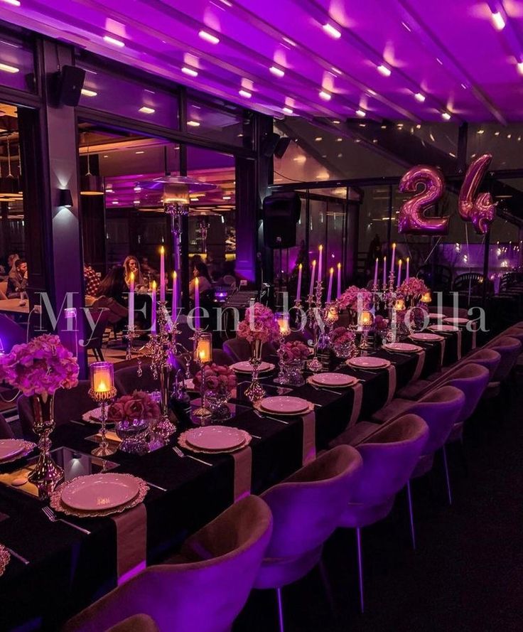 a long table is set up for a party with purple lighting and balloons in the background