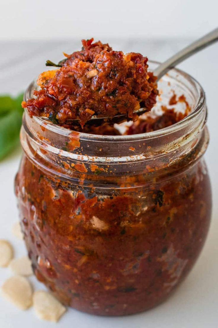 a jar filled with food sitting on top of a white table next to green peppers