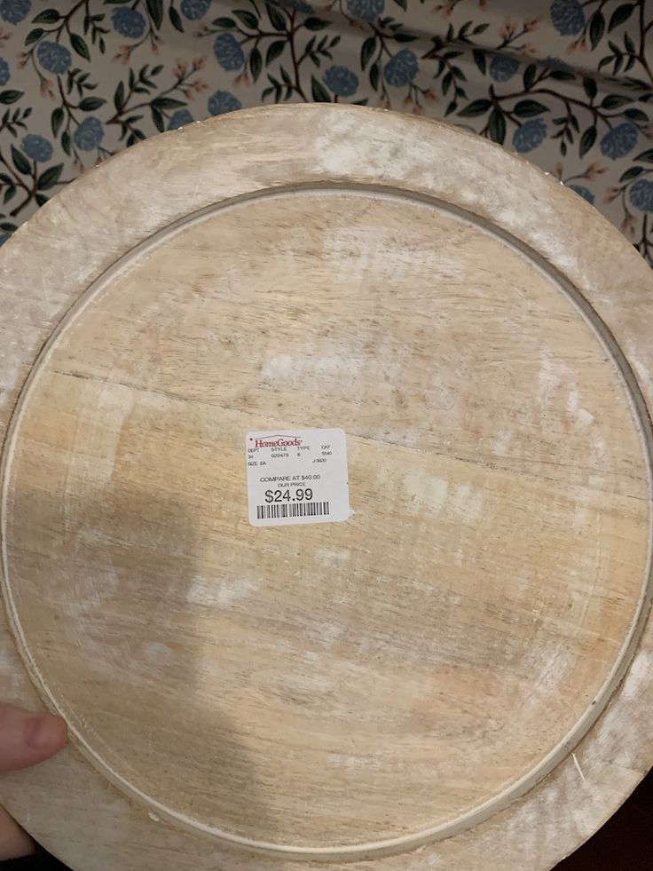 a person holding a wooden plate with a price tag on it's back side