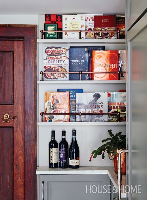 a book shelf filled with lots of books next to a door and potted plant