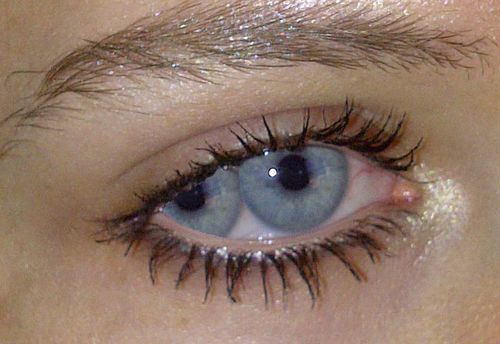 an eye with long lashes and blue eyeshadow is seen in this close up photo