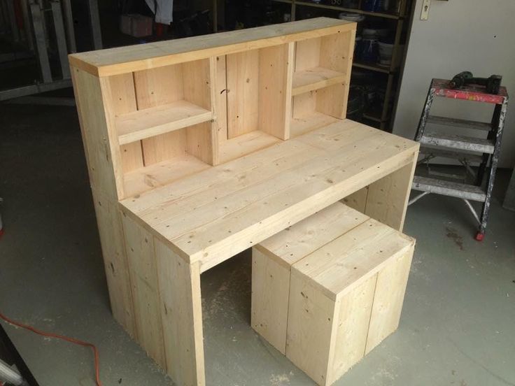 a wooden desk with shelves and drawers in a garage