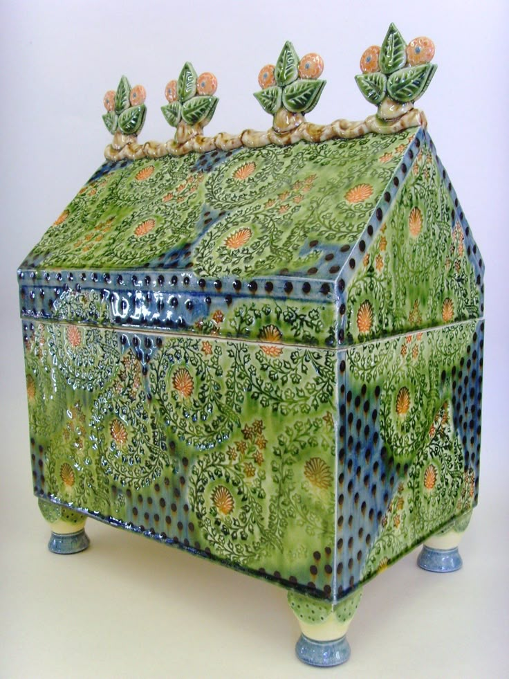 a green box with orange and blue designs on the lid sitting on top of a table