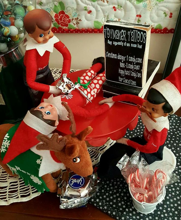 three elfs sitting at a table with candy canes and candies in front of them