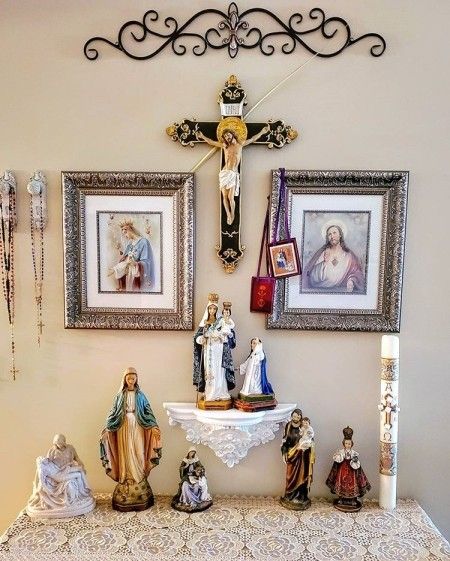 a table topped with pictures and figurines next to a wall mounted crucifix