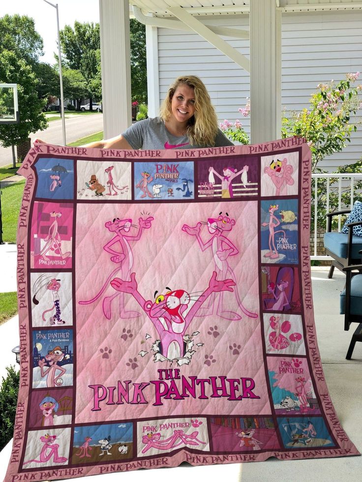 a woman holding up a pink panther quilt