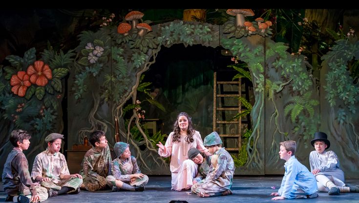 children sitting on the ground in front of a stage