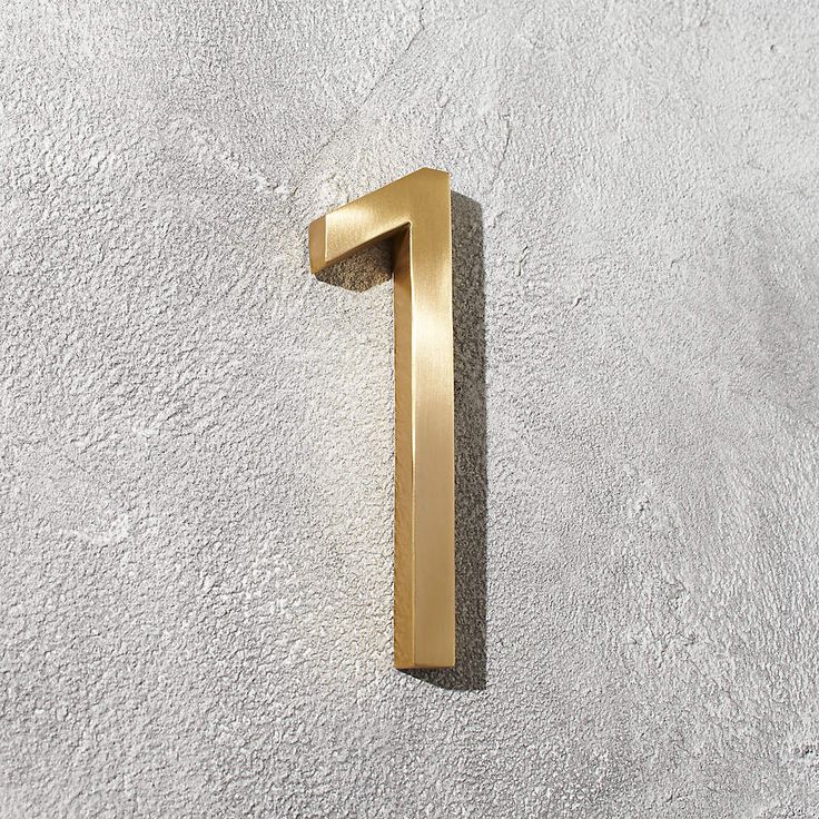 the number one is shown in gold on a white wall with grey concrete flooring