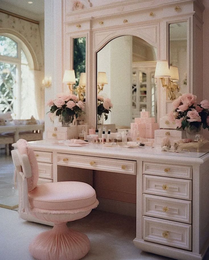 a white vanity with pink flowers on it and a chair in front of the mirror