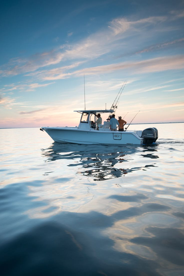 two people on a boat fishing in the ocean at sunset or dawn with one person standing up