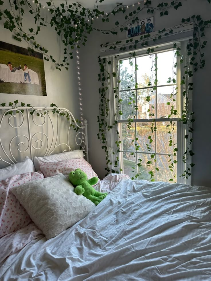 a white bed topped with pillows and a green teddy bear sitting on top of it