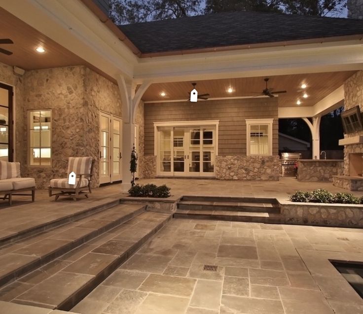 an outdoor living area with stone steps leading up to the front door and patio at night