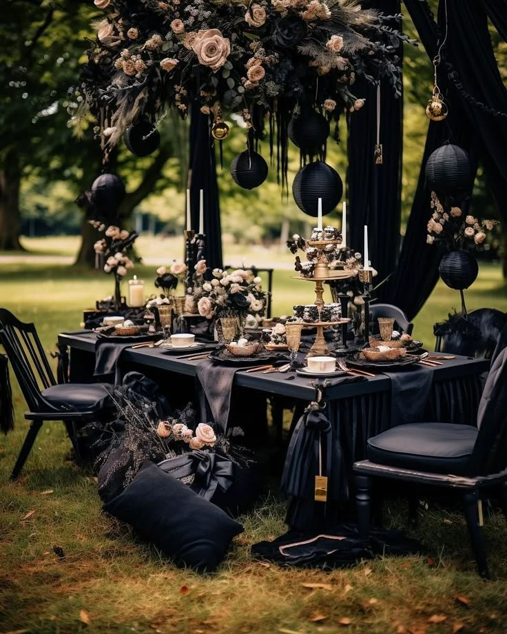 a table set up with black linens and flowers for an elegant dinner in the park