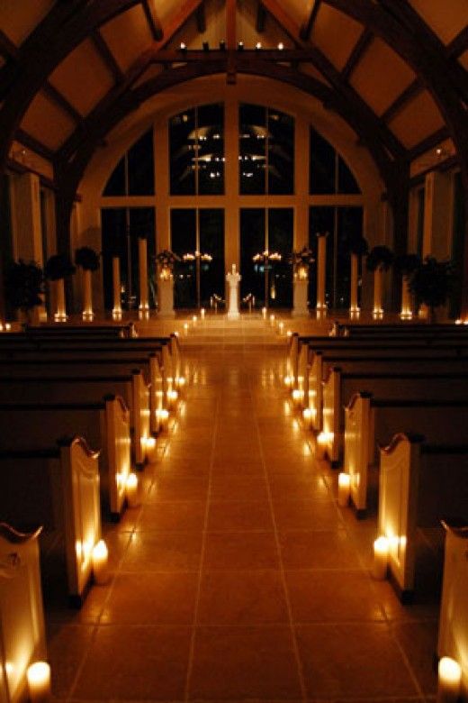 candles are lit in the aisle of a church