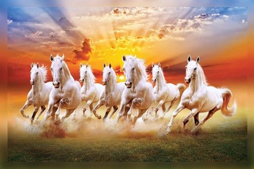 a group of white horses running across a field with the sun setting in the background