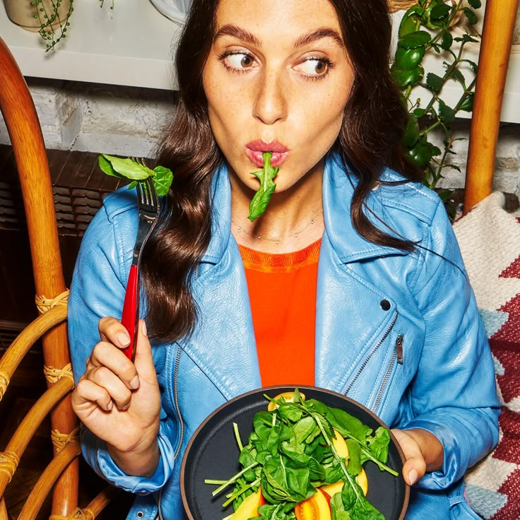 a woman is holding a plate with vegetables in it and making a funny face at the camera