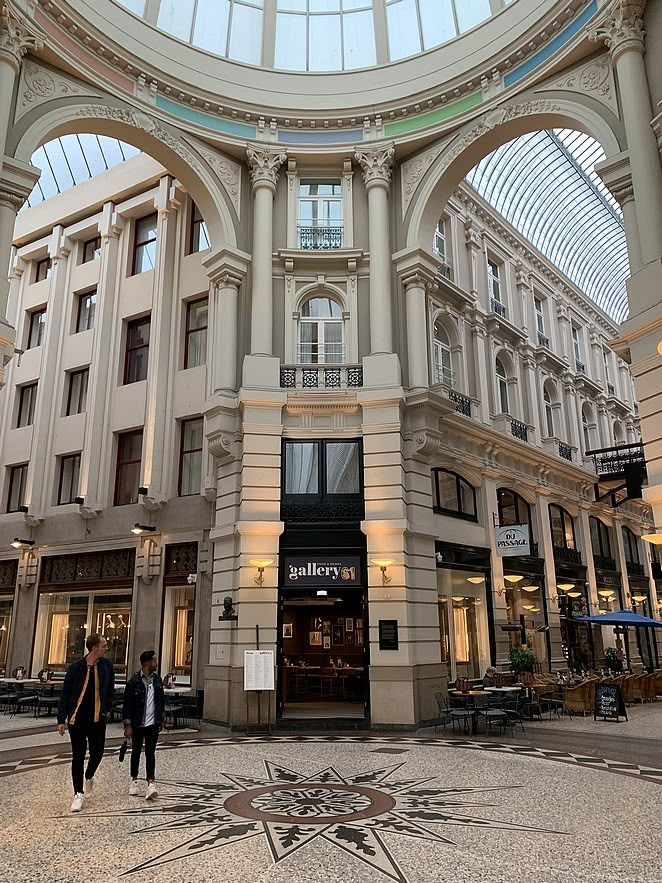 two people are walking in the middle of a shopping mall with an arch above them