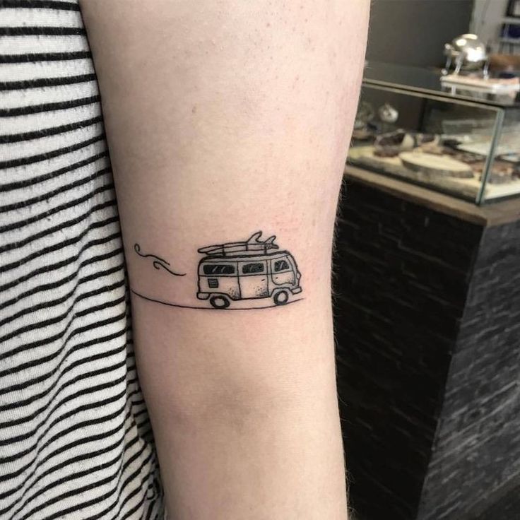 a woman's arm with a small tattoo of a van and surfboard on it