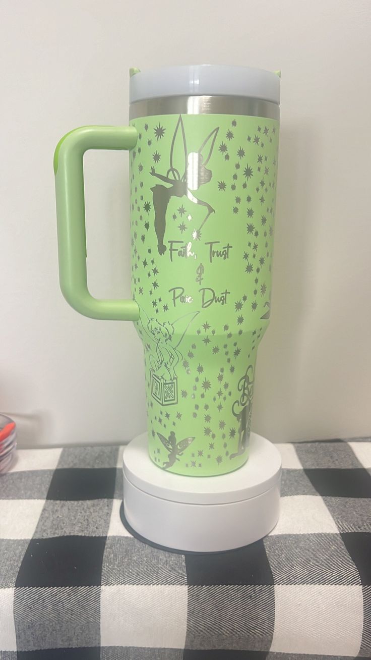 a green coffee cup sitting on top of a checkered table cloth