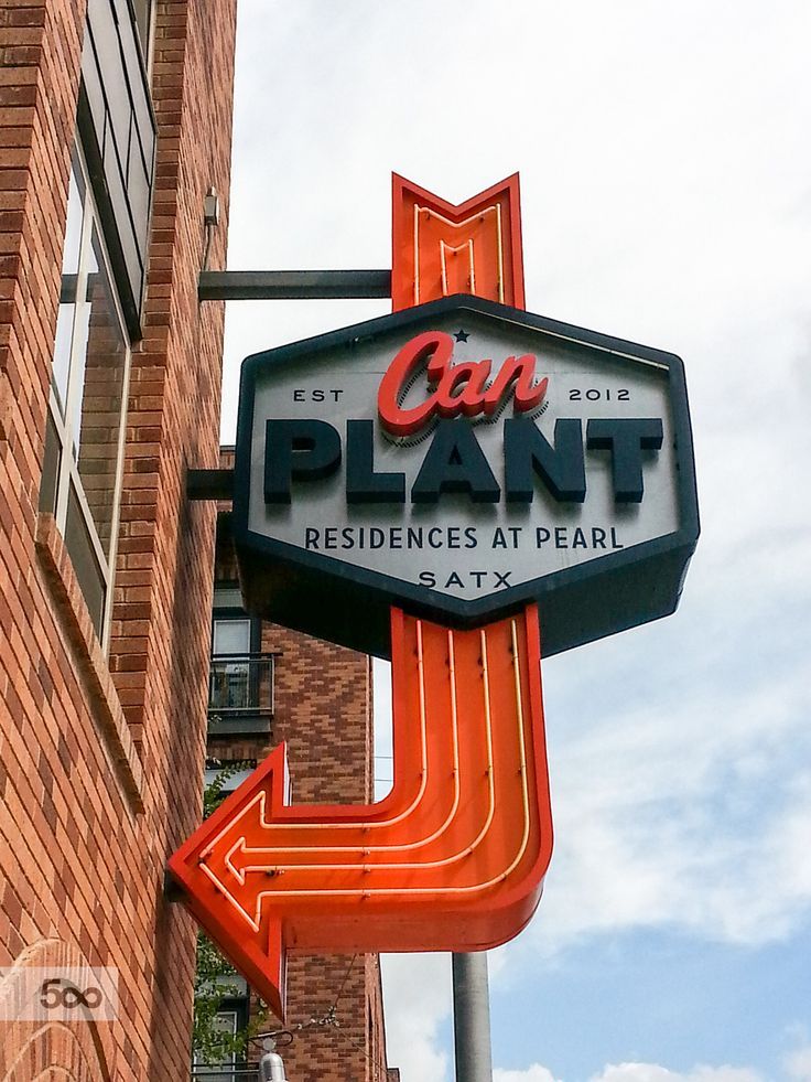 a neon sign for a plant that is on the side of a building with an arrow pointing to it