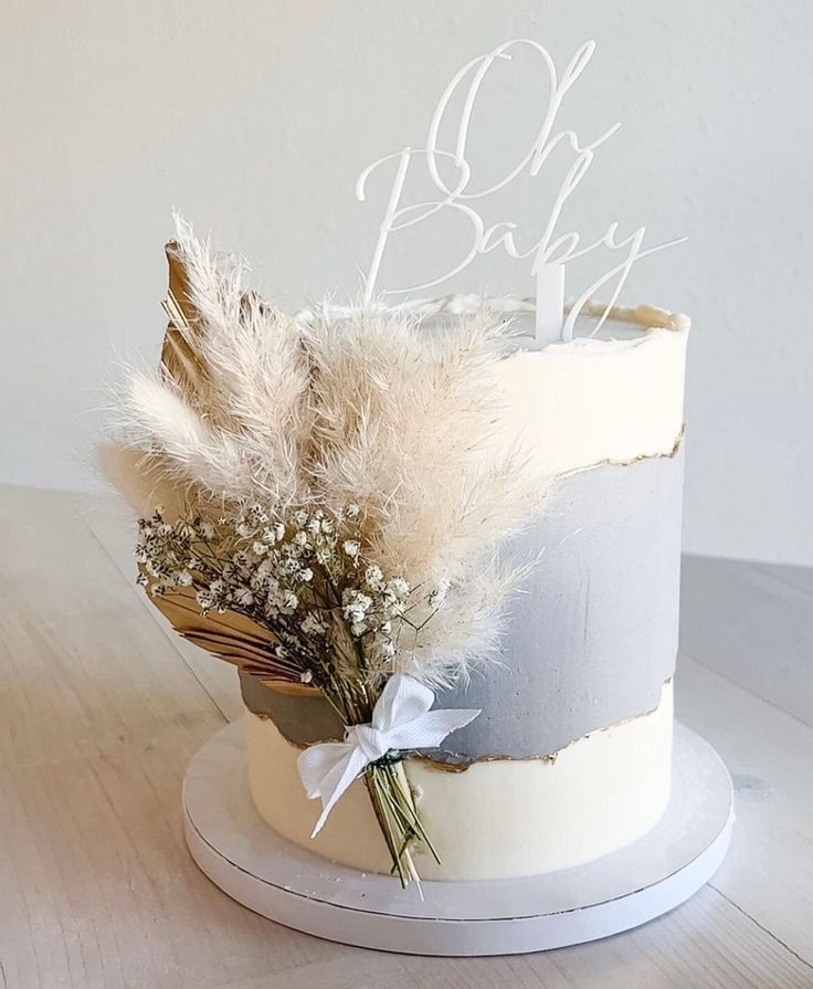 a white cake with feathers and baby's breath written on the top is sitting on a wooden table