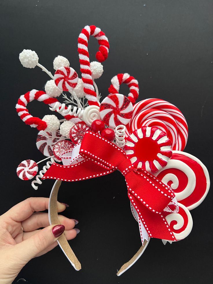 a person holding up a candy cane headband with red and white candies on it