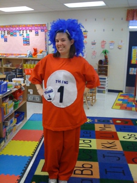 a woman in an orange shirt and blue hair is standing on the floor with her hands behind her back