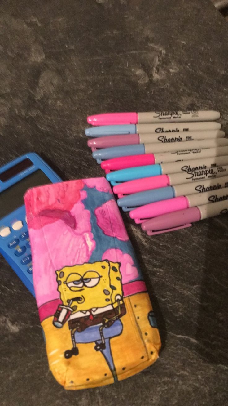 a cell phone sitting on top of a table next to some markers and pen holders