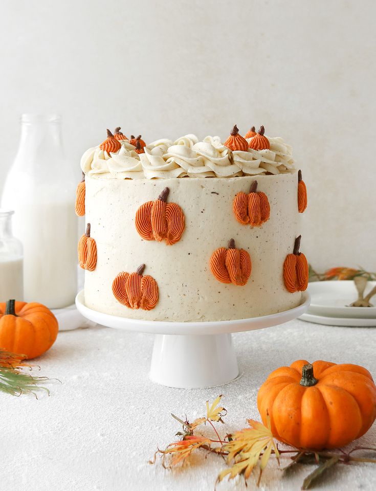 a cake with frosting and pumpkins on it sitting on a table next to other decorations