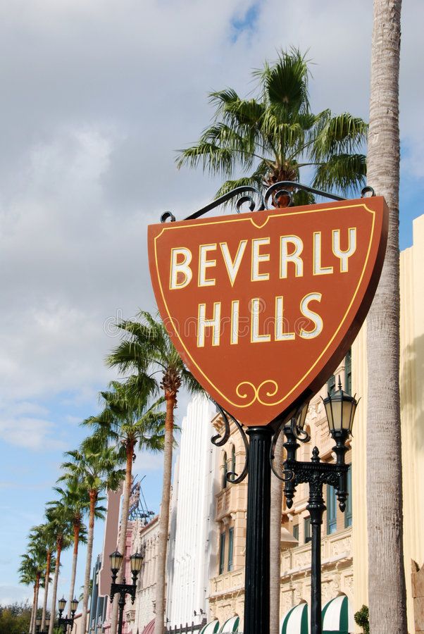 a sign for beverly hills on the side of a building in front of palm trees