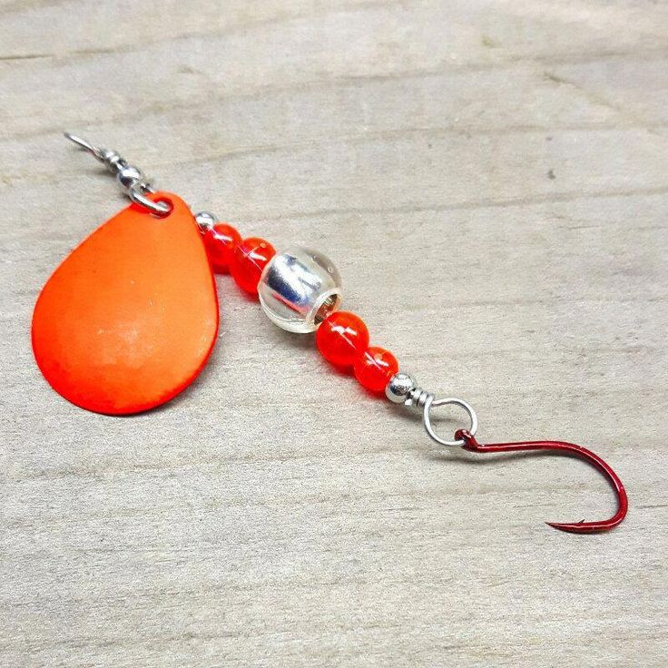 an orange and red fishing hook on a wooden surface with beads hanging from it's end