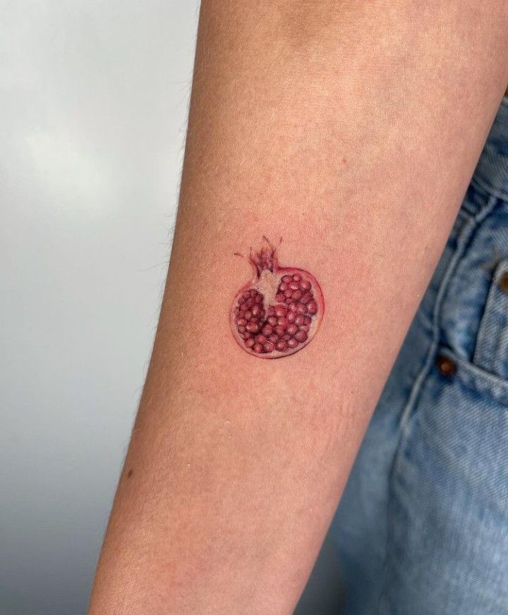 a small pomegranate tattoo on the arm