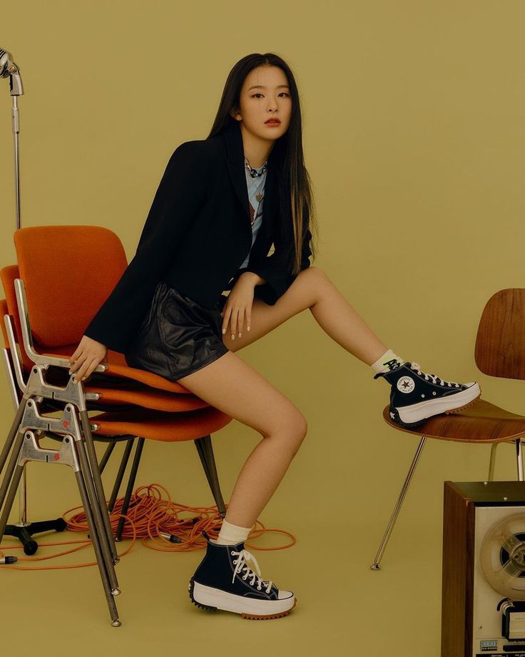 a woman sitting on top of a chair next to an orange chair and a radio