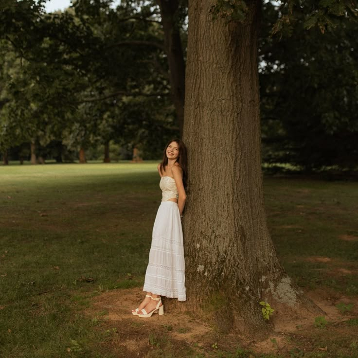 a woman leaning against a tree in a park