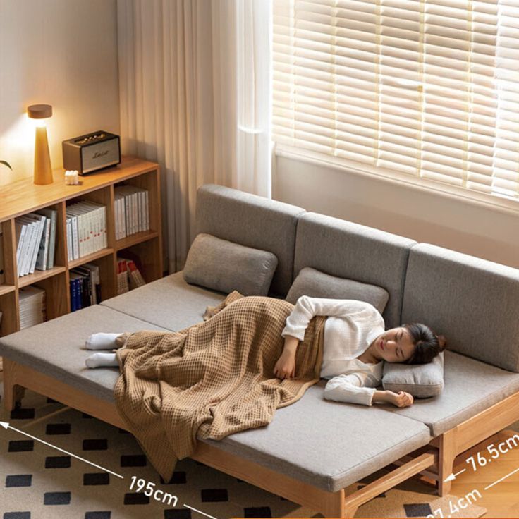 a woman laying on top of a couch next to a window