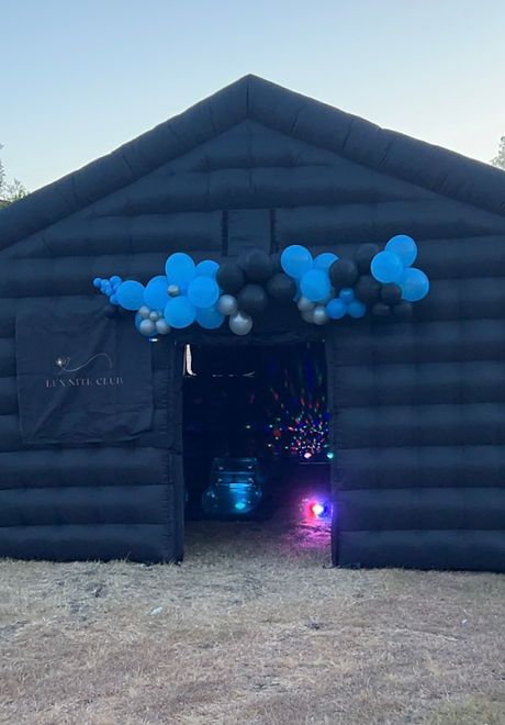 an inflatable barn with balloons and mickey mouse ears on the front door for decoration