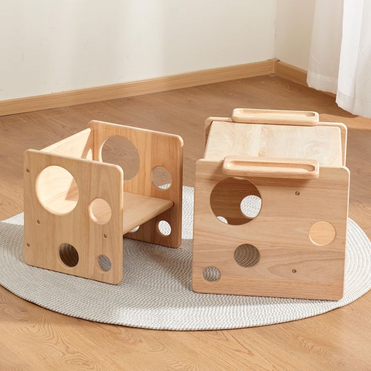 two wooden toys sitting on top of a white rug