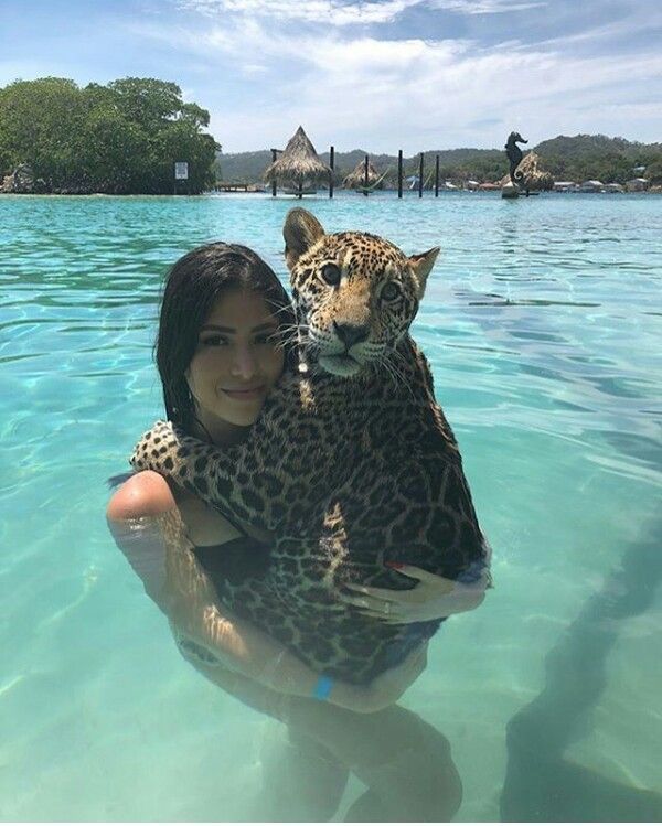 a woman holding a leopard in the water