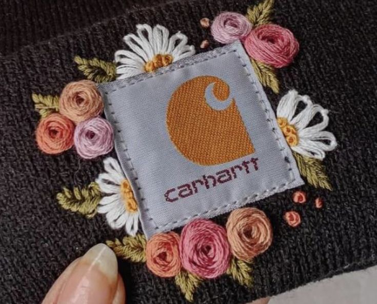 someone is stitching flowers on the back of a beanie with an applique