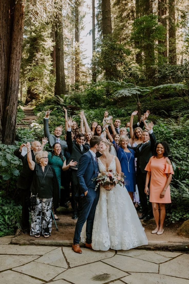 a group of people that are standing in the dirt near some trees and bushes with their hands up