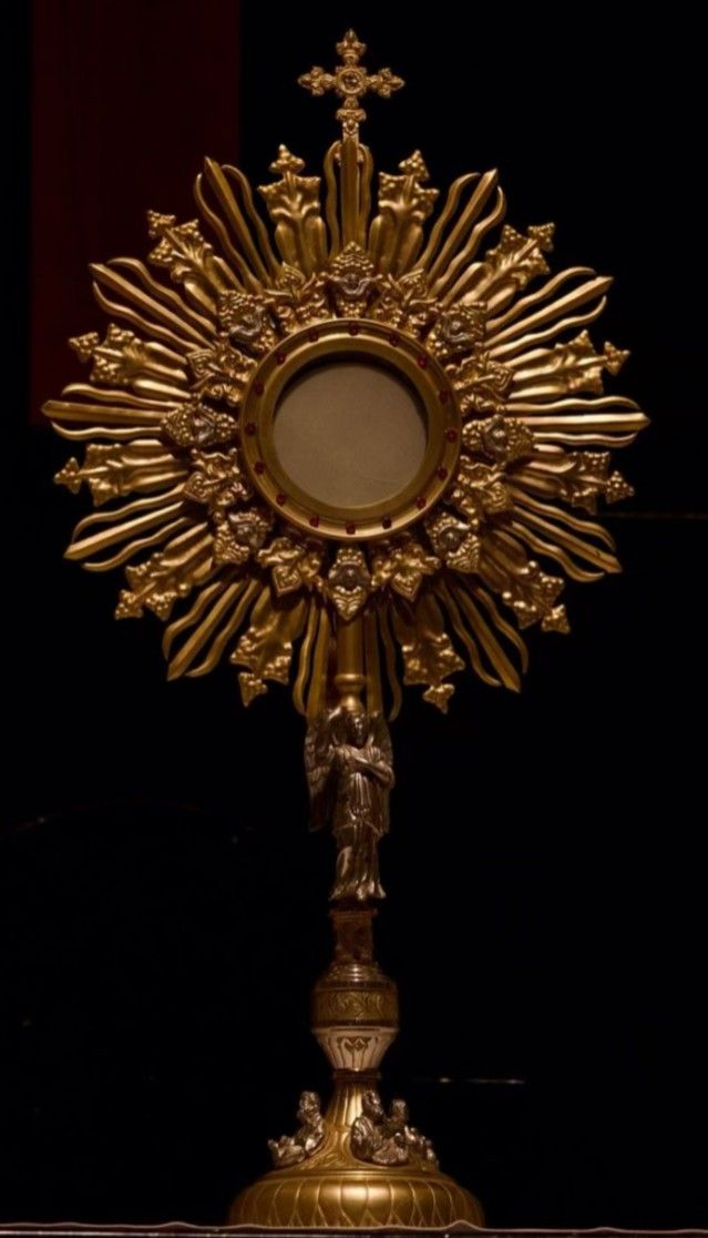 an ornate gold cross on top of a black table with a mirror in the middle