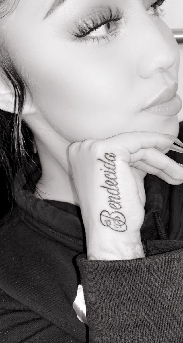 a woman with a tattoo on her arm looking at the camera and holding her hand to her face