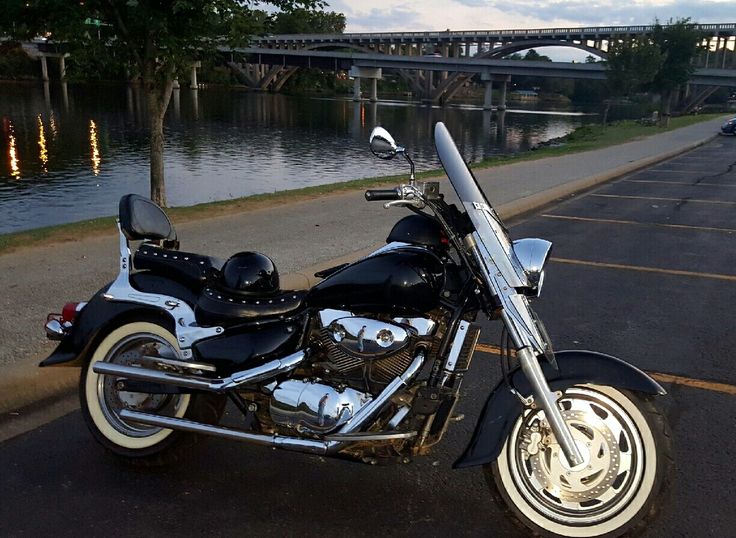 a black motorcycle parked on the side of a road next to a body of water