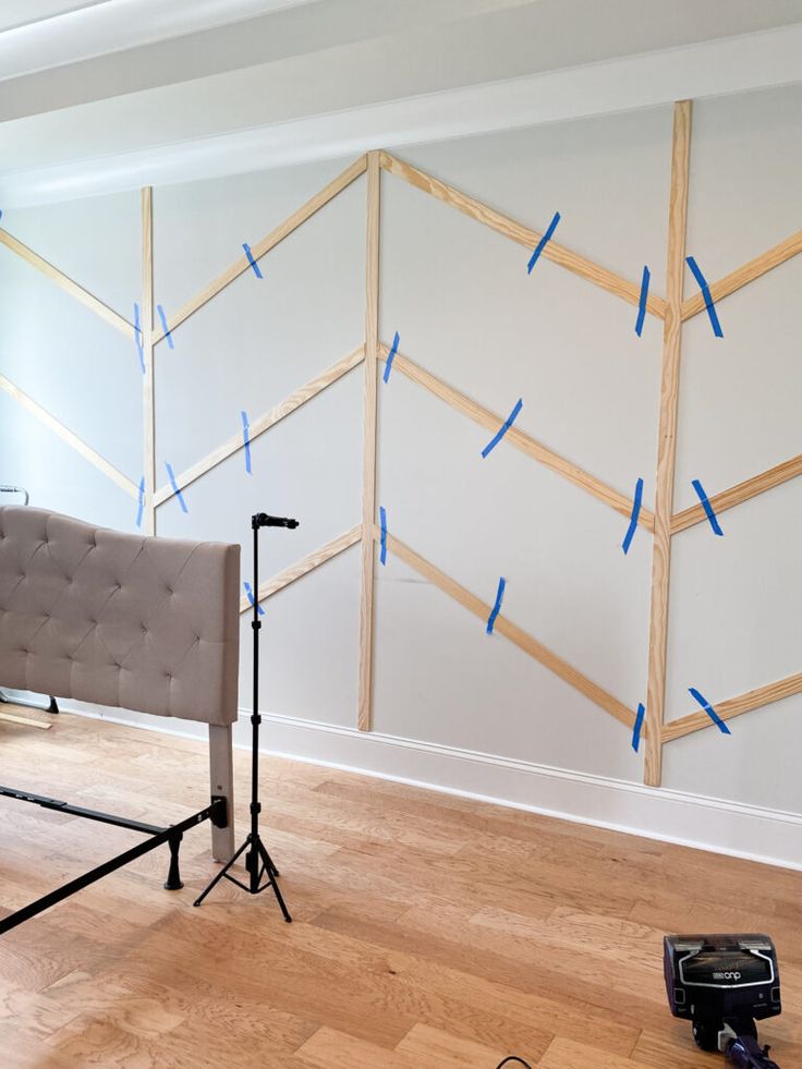 a couch sitting on top of a hard wood floor next to a wall covered in blue tape