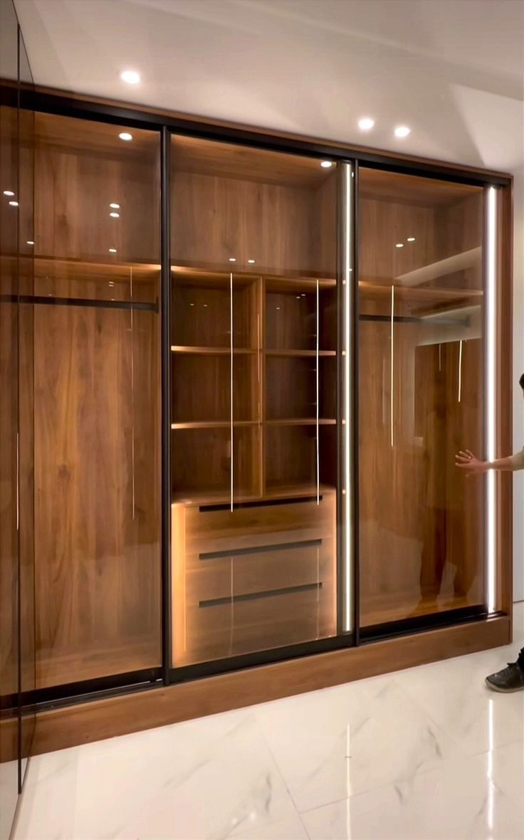 a man is standing in front of some closets with glass doors and lights on them