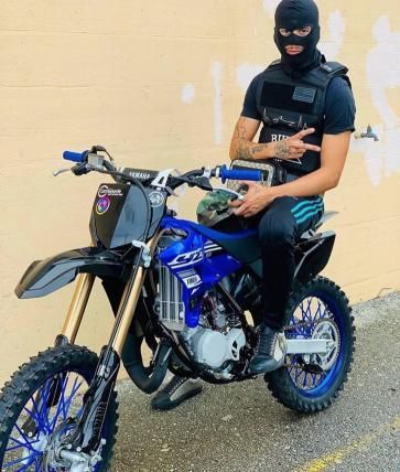 a man sitting on top of a blue dirt bike