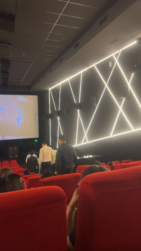 people are sitting in red chairs and watching a movie on the screen at an auditorium