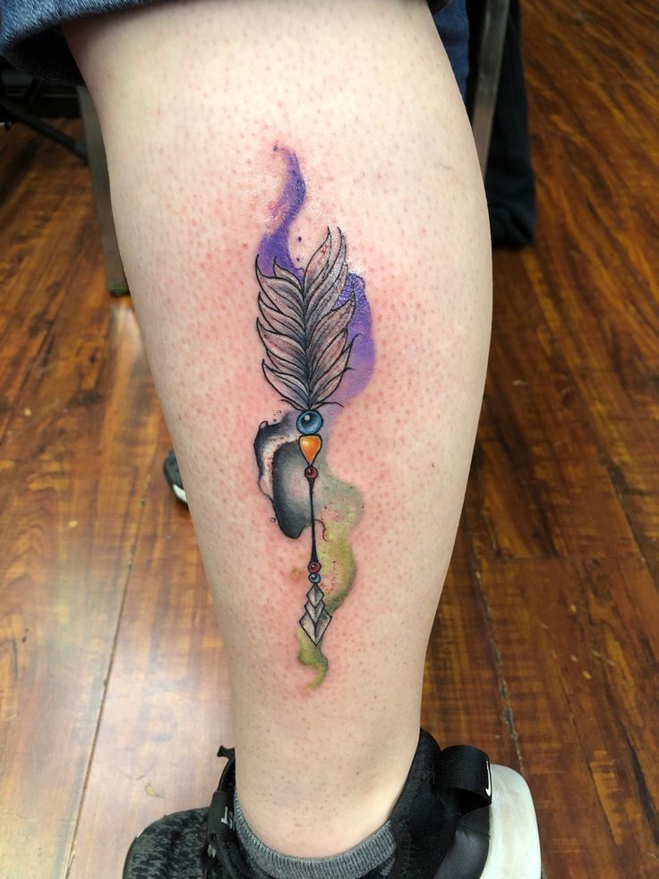 a tattoo on the leg of a person with a feather and an acrobat