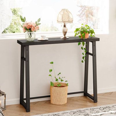 a table with plants on it in front of a window and a lamp next to it